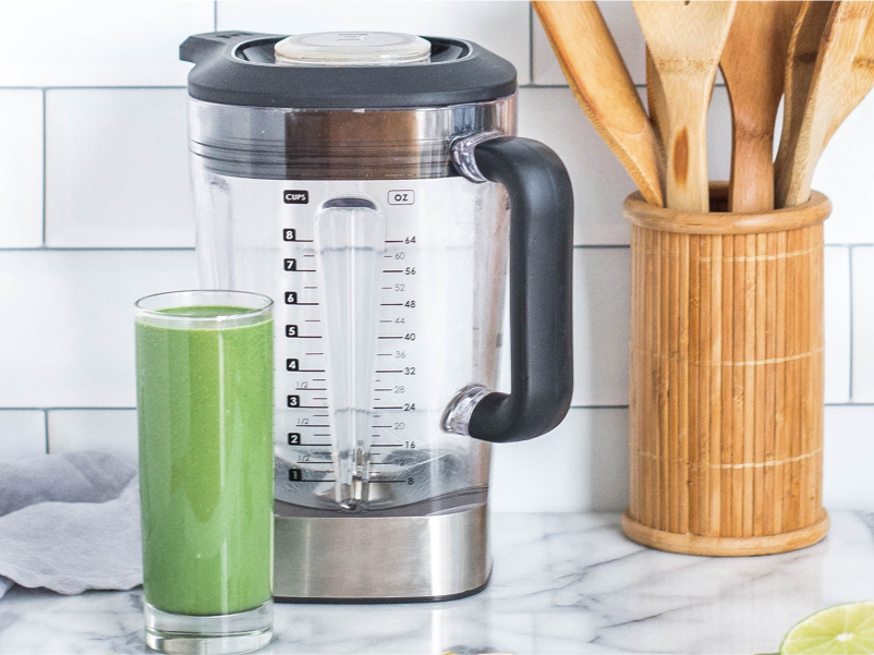 Healthy green juice next to a blender on a countertop